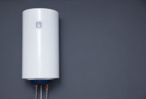 Modern electric boiler on a gray plain wall.