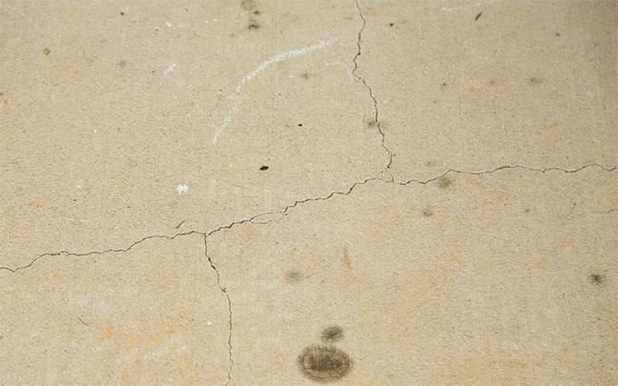 Old, dirty concrete patio with several ugly hairline cracks from expansion and contraction