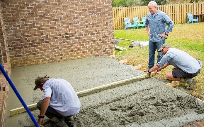 Danny Lipford oversees contractors as they pour a concrete slab for a patio.