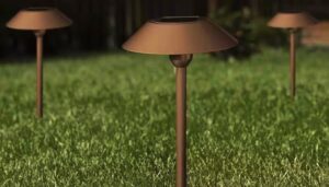 Bronze-colored Feit Electric Landscape Lights, seen staked into a lush green lawn.
