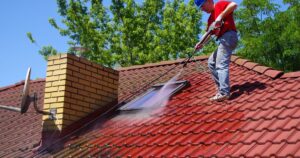 man pressure washing roof