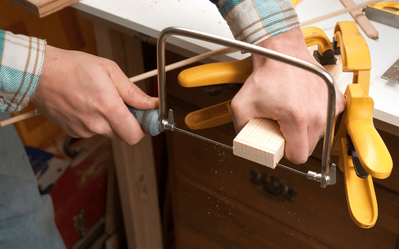 person cutting wood with a coping saw